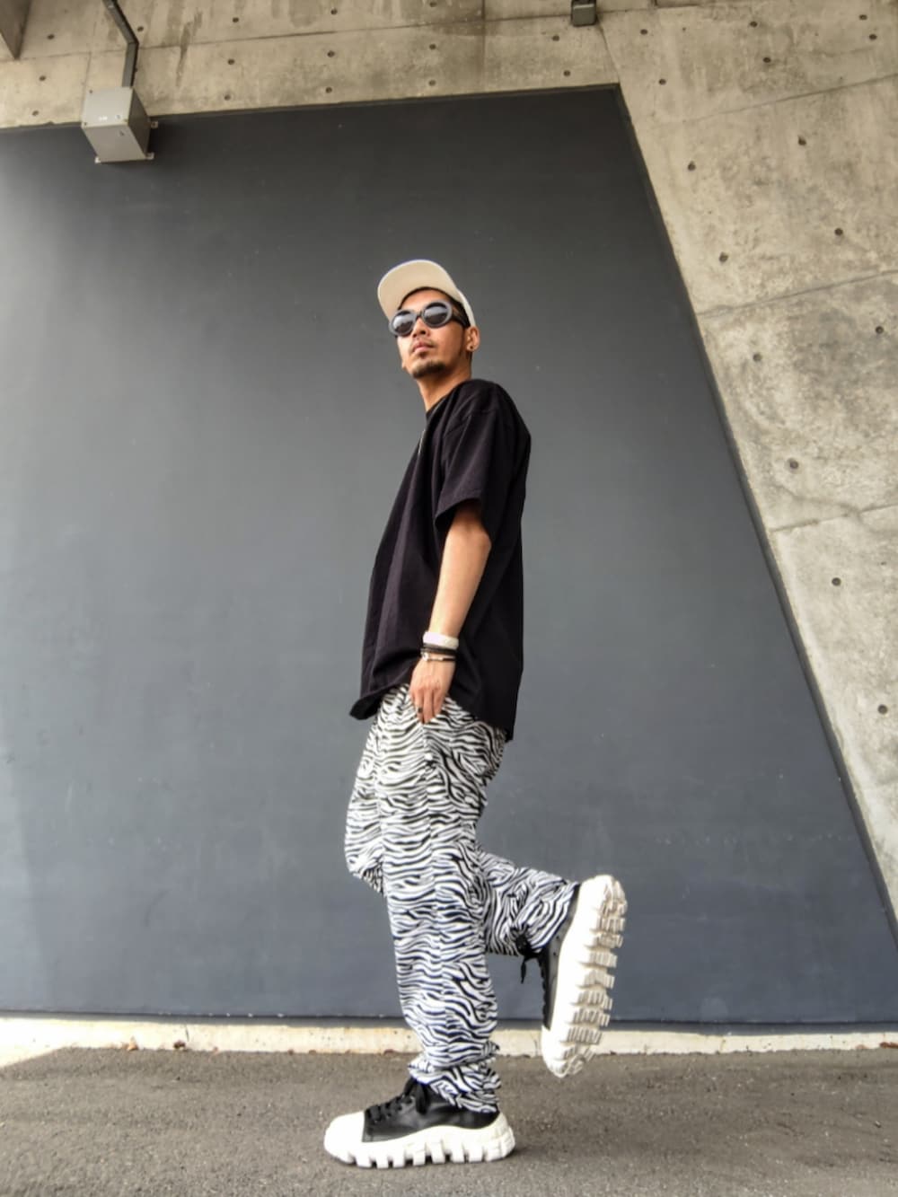 ブラック系のTシャツ/カットソー、ホワイト系のその他パンツ、その他のスニーカーを着用したメンズの春コーディネートの2枚目の写真