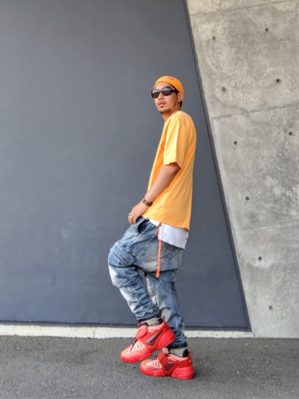 オレンジ系のTシャツ/カットソー、ホワイト系のタンクトップ、ブルー系のデニムパンツを着用したメンズの夏コーディネートの2枚目の写真