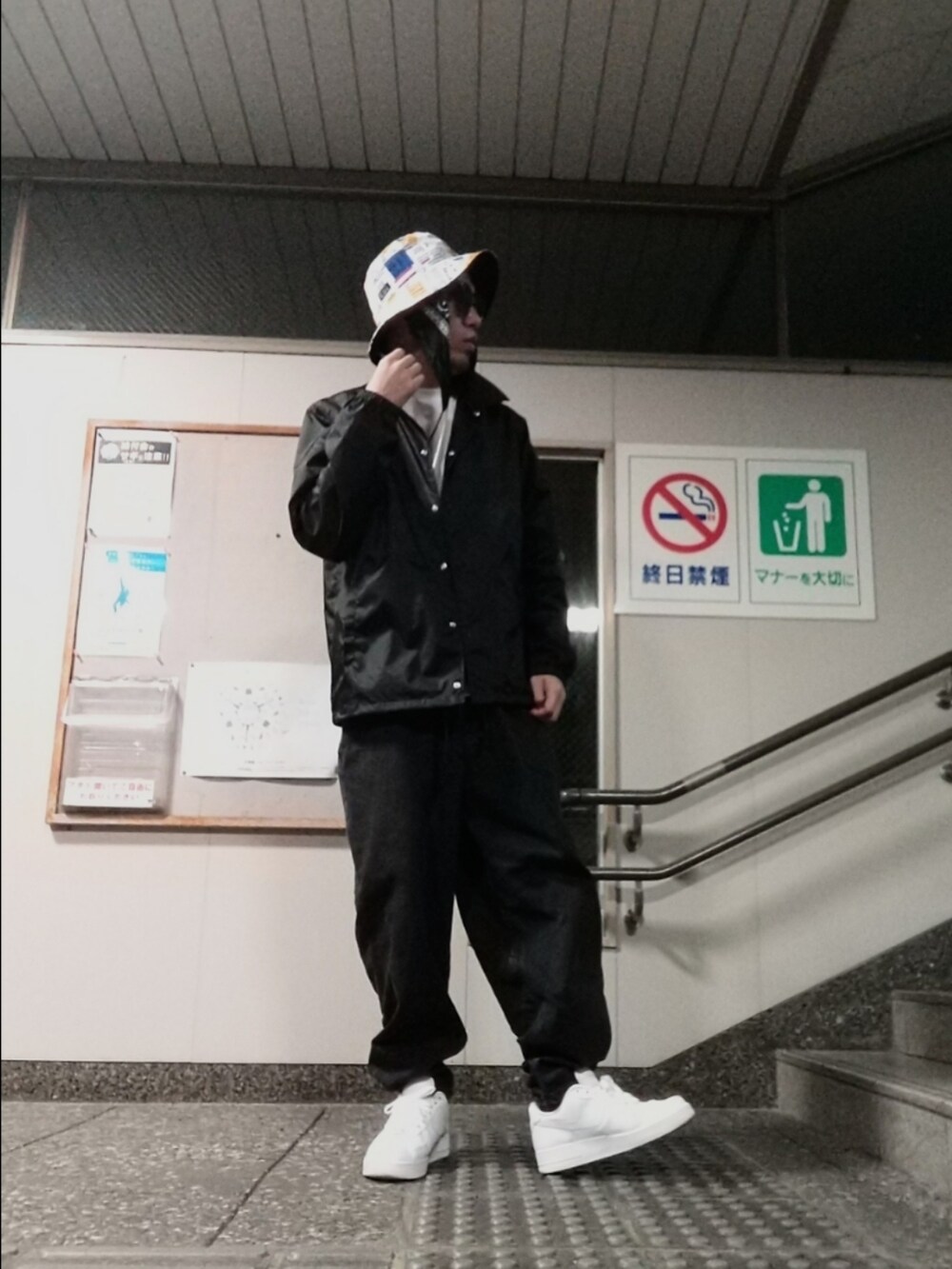 ホワイト系のスニーカー、ブルー系のナイロンジャケット、ブラック系のデニムパンツを着用したメンズの春コーディネートの3枚目の写真