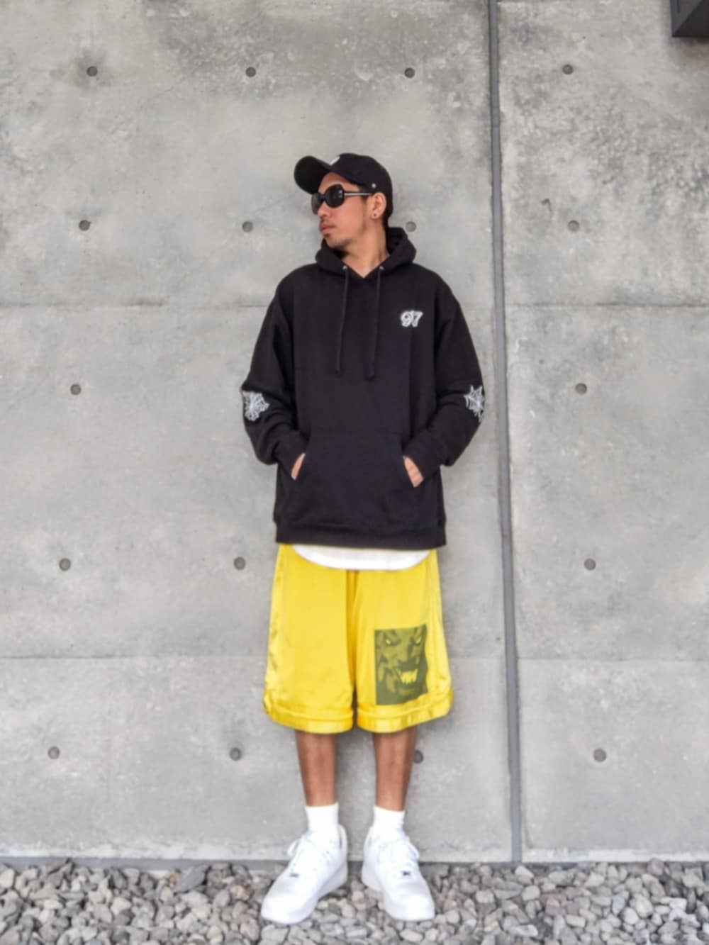 ブラック系のパーカー、ホワイト系のタンクトップ、イエロー系のその他パンツを着用したメンズの春コーディネートの2枚目の写真