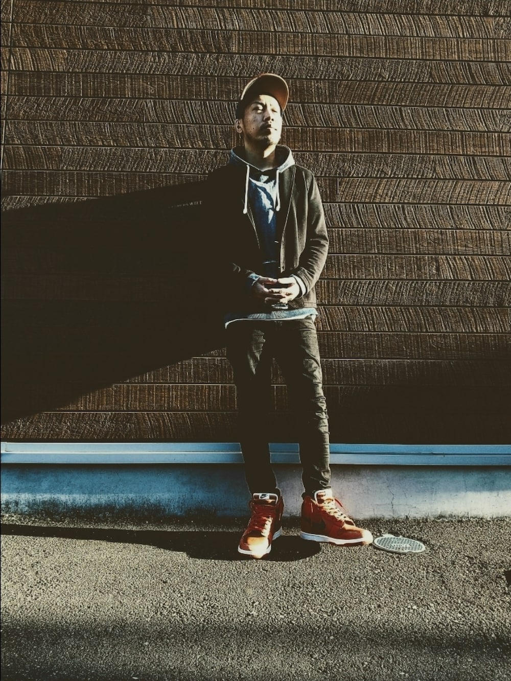 ブルー系のパーカー、ブラック系のデニムパンツ、オレンジ系のスニーカーを着用したメンズの秋コーディネートの2枚目の写真