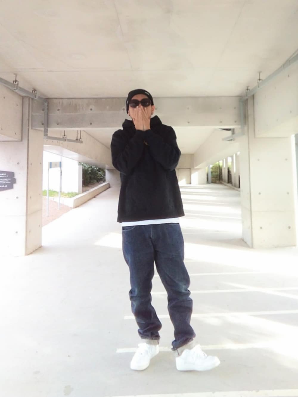 ブラック系のパーカー、ブルー系のデニムパンツ、ホワイト系のスニーカーを着用したメンズの冬コーディネートの3枚目の写真