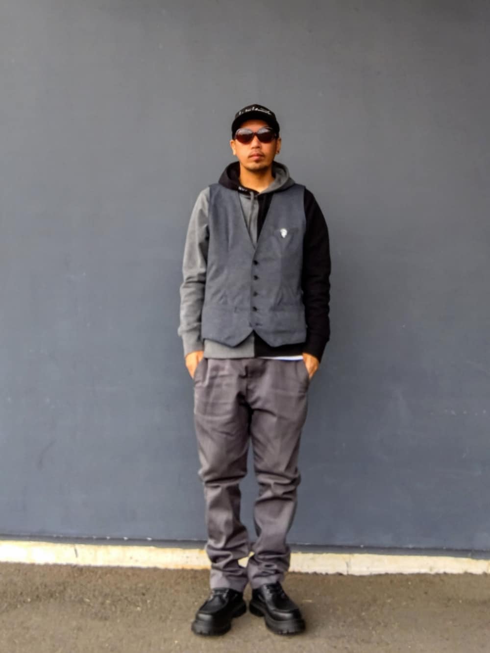 グレー系のベスト、ブラック系のパーカー、グレー系のチノパンツを着用したメンズの冬コーディネートの2枚目の写真