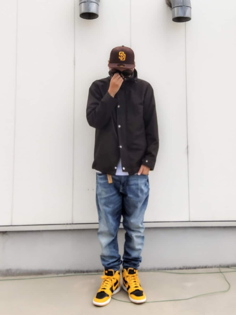 ブラック系のマウンテンパーカー、ホワイト系のTシャツ/カットソー、ブルー系のデニムパンツを着用したメンズの秋コーディネートの3枚目の写真