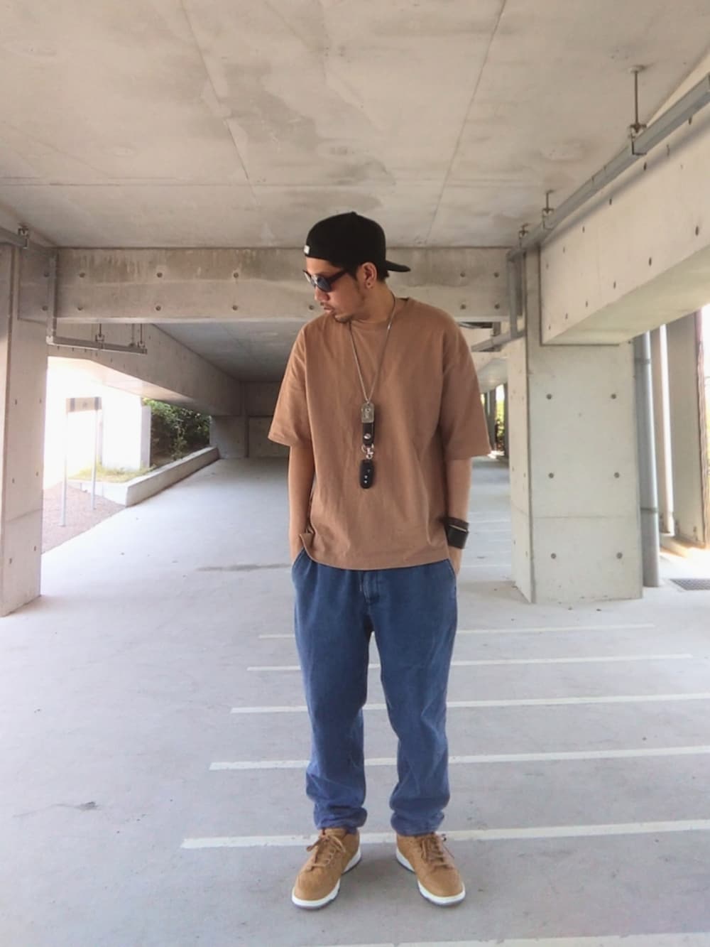 ブラウン系のスニーカー、ブラウン系のTシャツ/カットソー、ブルー系のデニムパンツを着用したメンズの夏コーディネートの2枚目の写真
