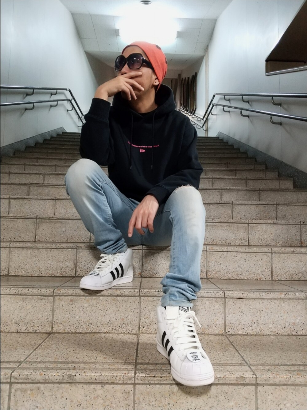 ブラック系のパーカー、ブルー系のデニムパンツ、ホワイト系のスニーカーを着用したメンズの春コーディネートの3枚目の写真