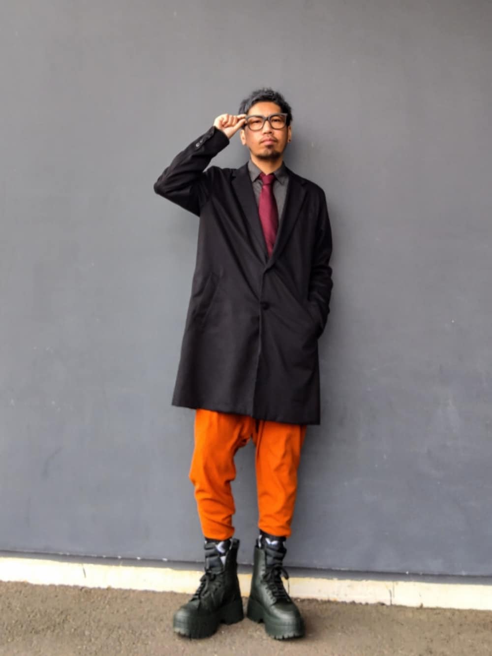 ブラック系のチェスターコート、ブラック系のシャツ/ブラウス、オレンジ系のその他パンツを着用したメンズの冬コーディネートの3枚目の写真