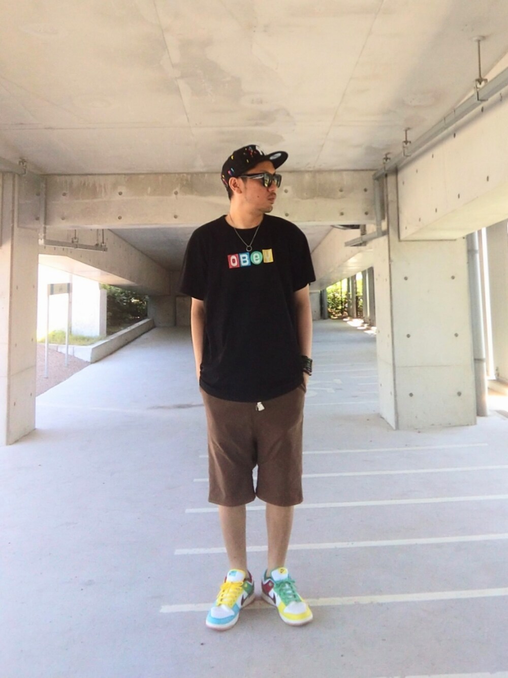 ブラック系のTシャツ/カットソー、ブラウン系のその他パンツ、その他のスニーカーを着用したメンズの夏コーディネートの2枚目の写真