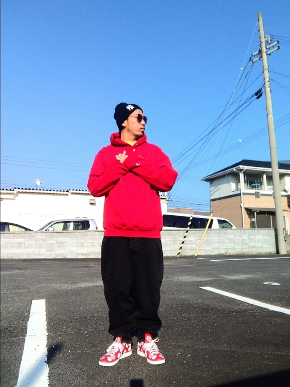 レッド系のパーカー、ブラック系のデニムパンツ、レッド系のスニーカーを着用したメンズの冬コーディネートの3枚目の写真