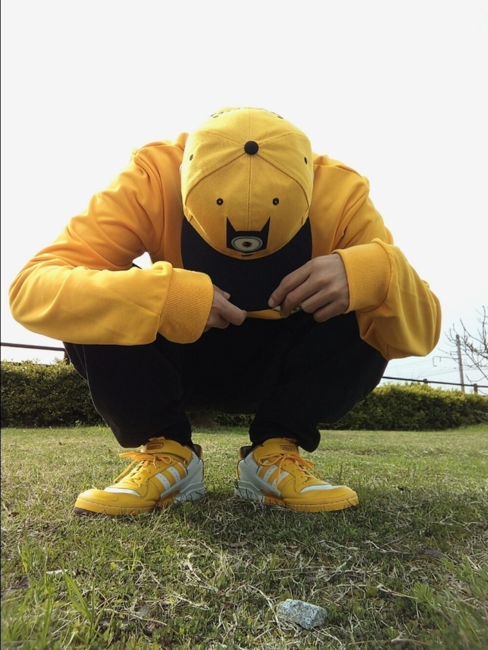 イエロー系のスウェット、ブラック系のデニムパンツ、イエロー系のスニーカーを着用したメンズの春コーディネートの3枚目の写真