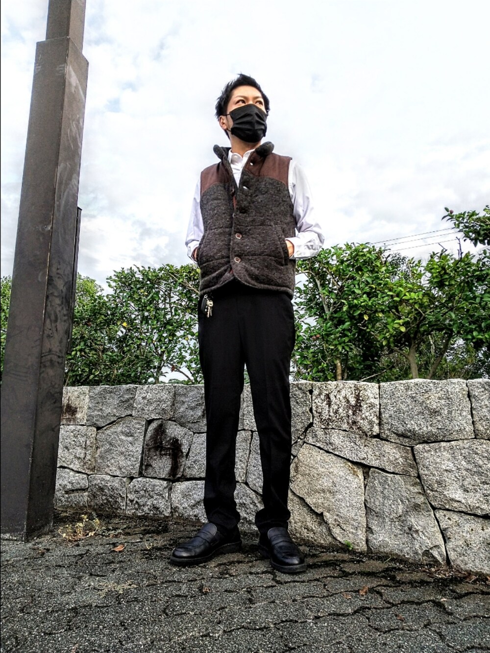 グレー系のベスト、ブラック系のスラックス、ブラック系のローファーを着用したメンズの秋コーディネートの2枚目の写真