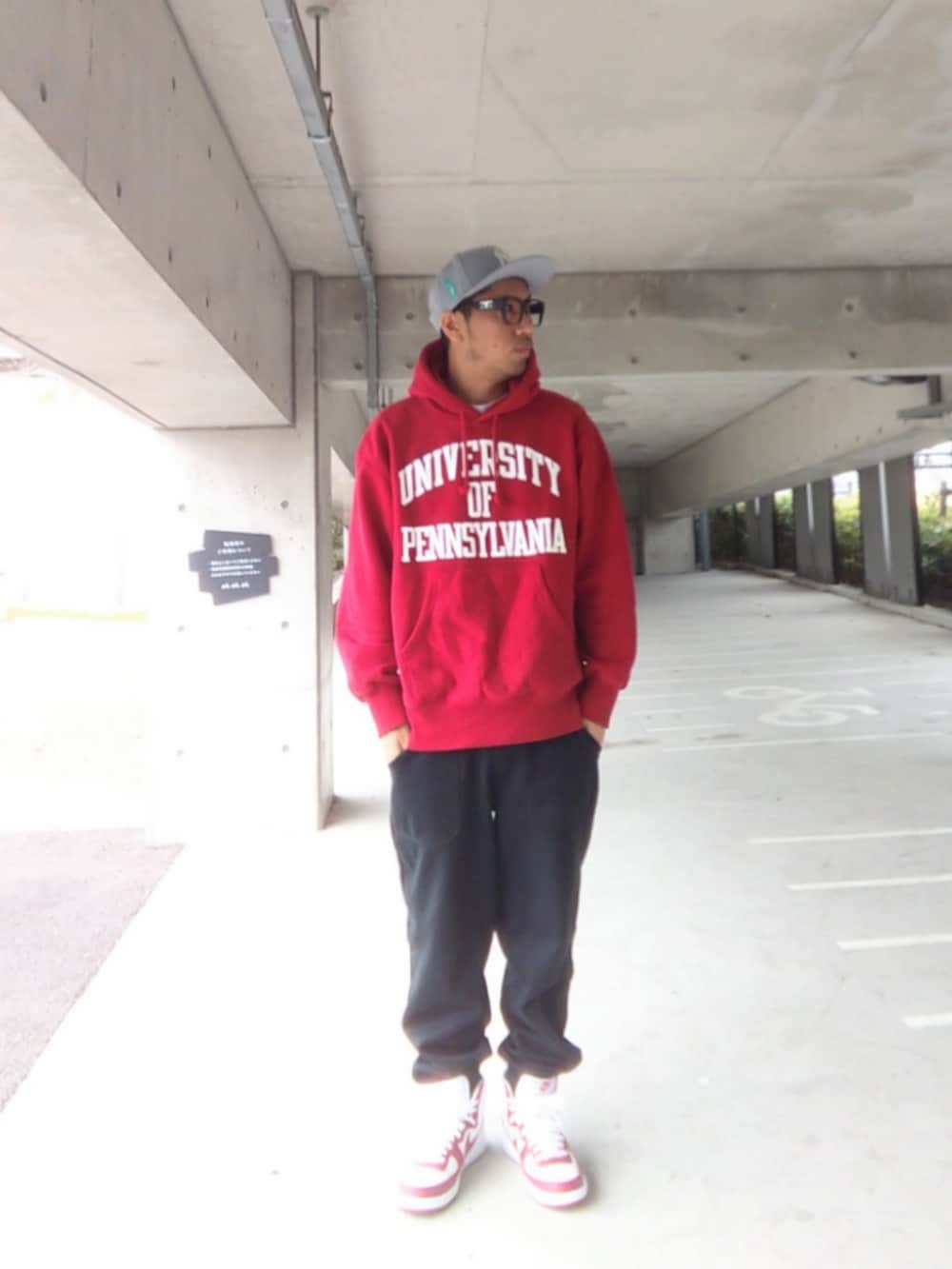 レッド系のパーカー、ブラック系のスウェットパンツ、ホワイト系のスニーカーを着用したメンズの春コーディネートの2枚目の写真