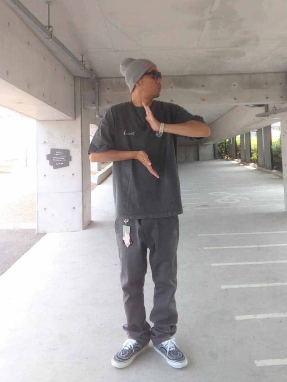 ブラック系のTシャツ/カットソー、グレー系のチノパンツ、ブラック系のスニーカーを着用したメンズの夏コーディネートの2枚目の写真