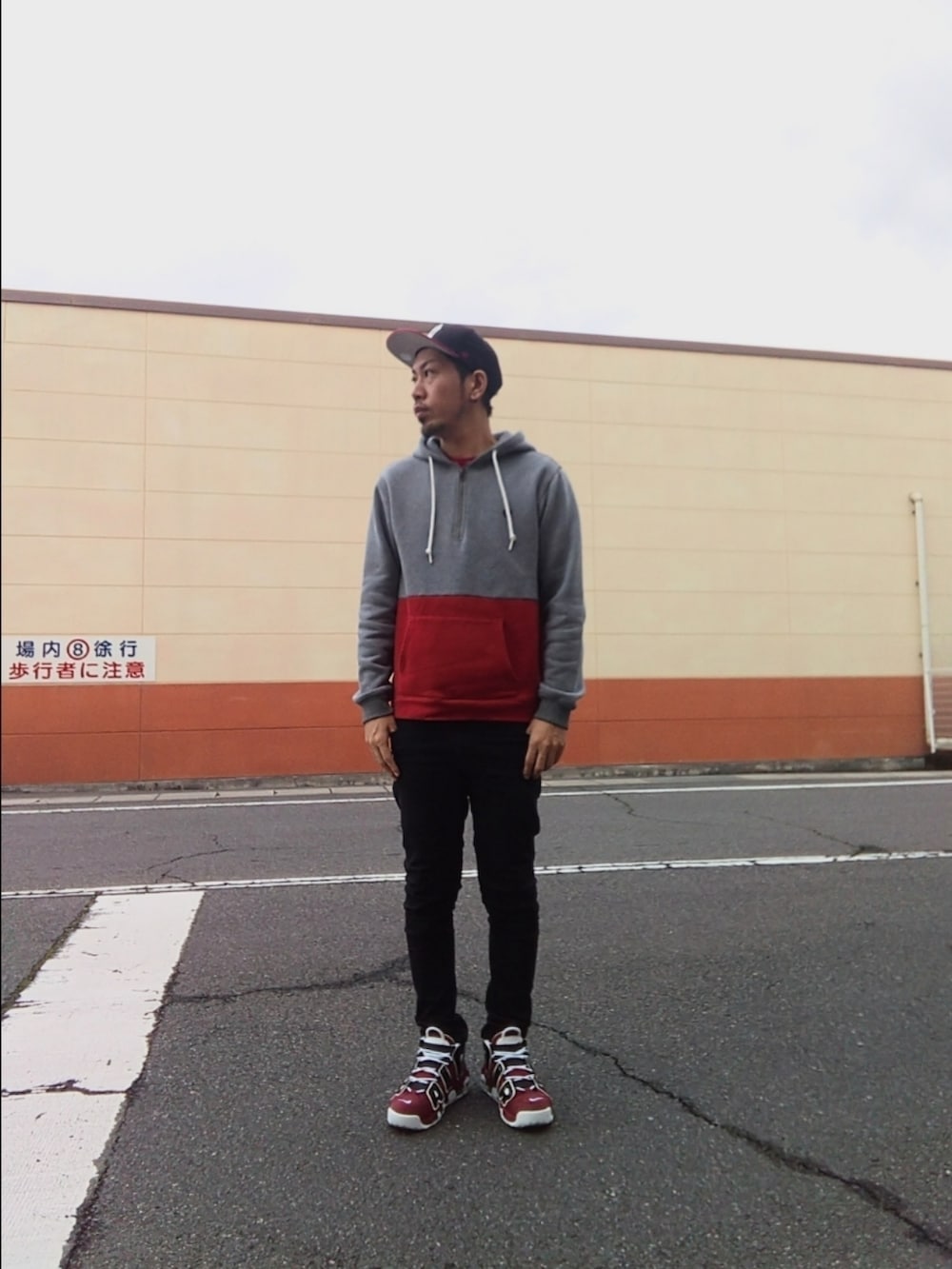 グレー系のパーカー、レッド系のスニーカー、ブラック系のデニムパンツを着用したメンズの春コーディネートの2枚目の写真