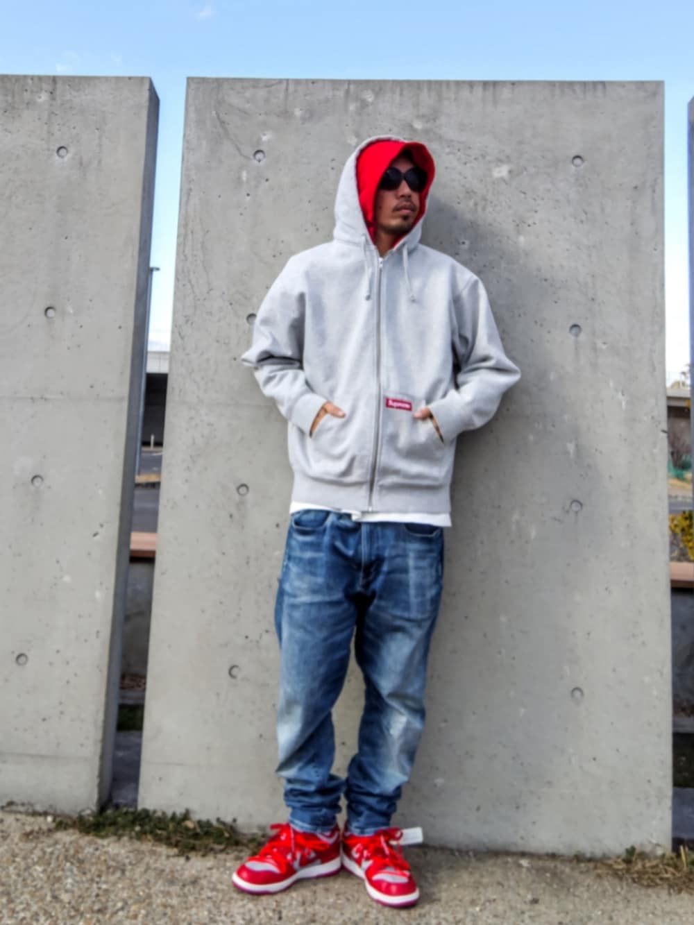 グレー系のパーカー、ブルー系のデニムパンツ、レッド系のスニーカーを着用したメンズの冬コーディネートの4枚目の写真