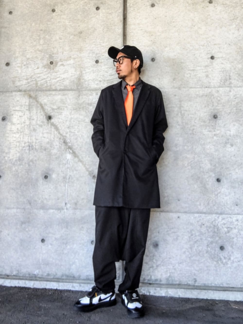 オレンジ系のネクタイ、ブラック系のチェスターコート、ブラック系のシャツ/ブラウスを着用したメンズの春コーディネートの2枚目の写真