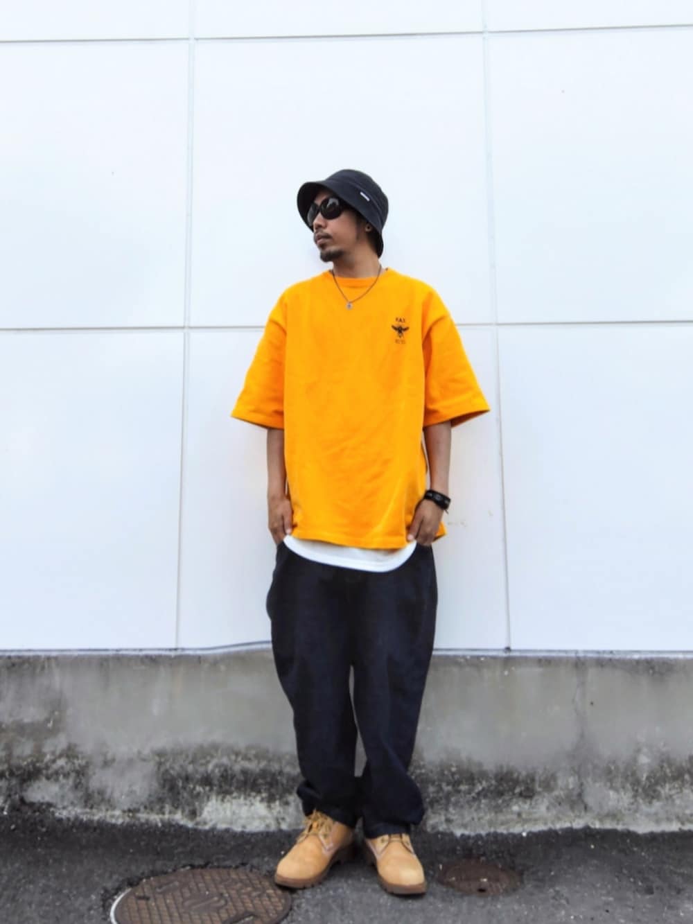 イエロー系のTシャツ/カットソー、ブルー系のデニムパンツ、イエロー系のブーツを着用したメンズの春コーディネートの2枚目の写真