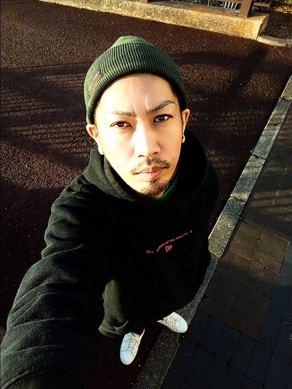 ブラック系のパーカー、グリーン系のTシャツ/カットソー、ブラック系のデニムパンツを着用したメンズの秋コーディネートの3枚目の写真