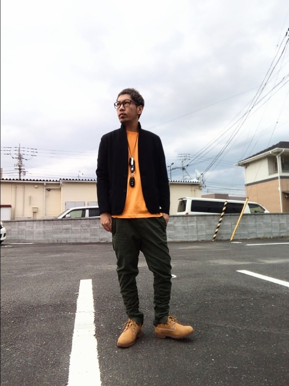 イエロー系のブーツ、グリーン系のパンツ、オレンジ系のTシャツ/カットソーを着用したメンズの冬コーディネートの3枚目の写真