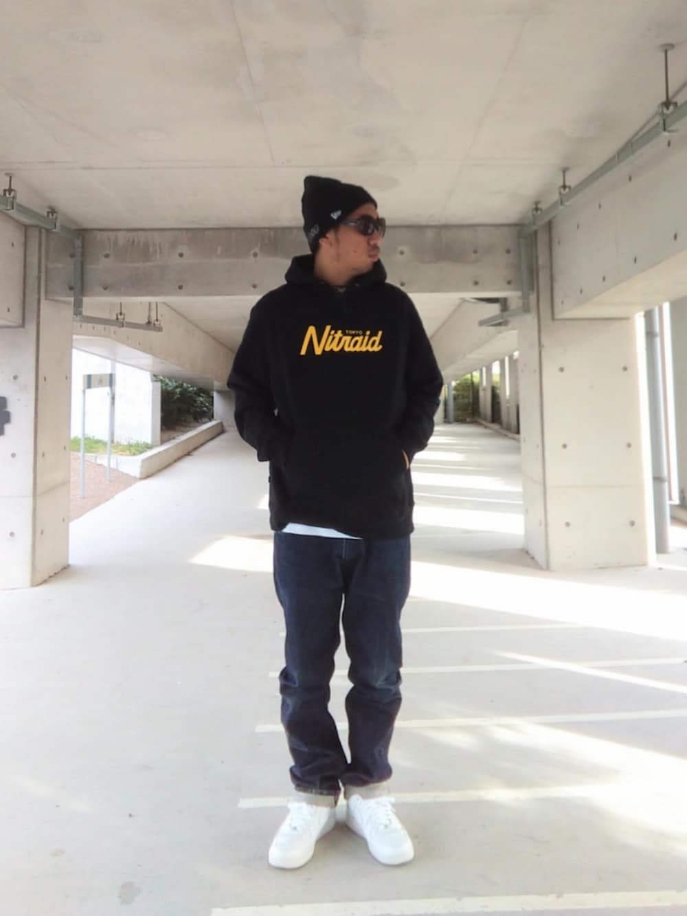 ブラック系のパーカー、ブルー系のデニムパンツ、ホワイト系のスニーカーを着用したメンズの冬コーディネートの2枚目の写真