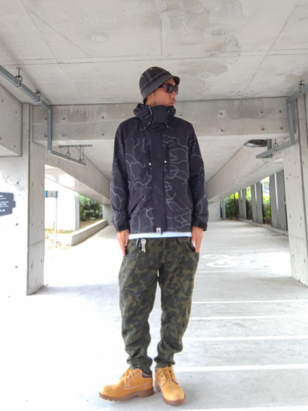 ブラック系のミリタリージャケット、ホワイト系のタンクトップ、その他のパンツを着用したメンズの秋コーディネートの2枚目の写真