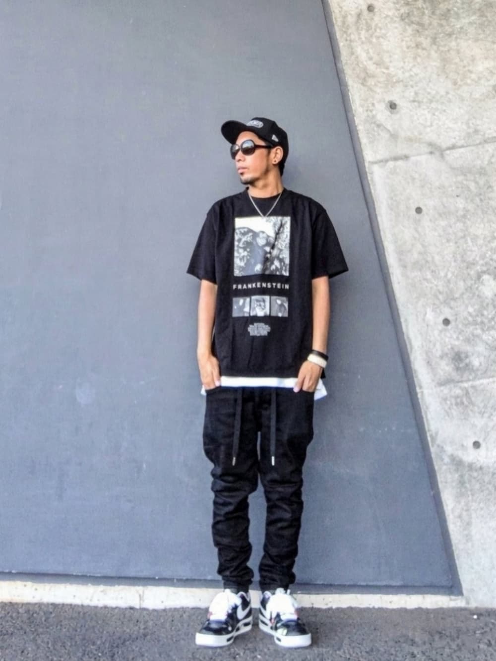 ブラック系のTシャツ/カットソー、ブラック系のデニムパンツ、ブラック系のスニーカーを着用したメンズの秋コーディネートの2枚目の写真