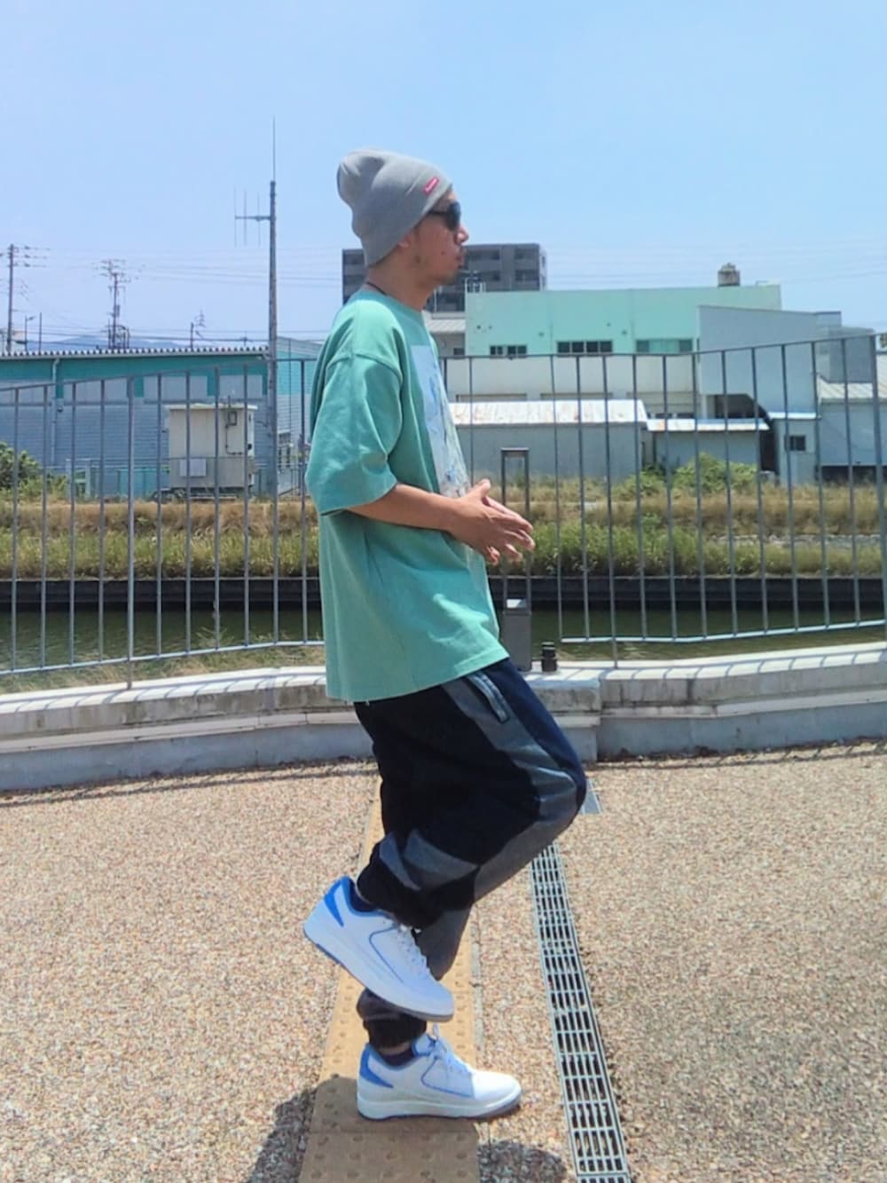 グリーン系のTシャツ/カットソー、ブルー系のデニムパンツ、ホワイト系のスニーカーを着用したメンズの夏コーディネートの2枚目の写真