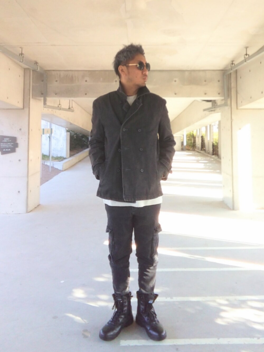 ブラック系のピーコート、ホワイト系のニット/セーター、ブラック系のデニムパンツを着用したメンズの冬コーディネートの2枚目の写真