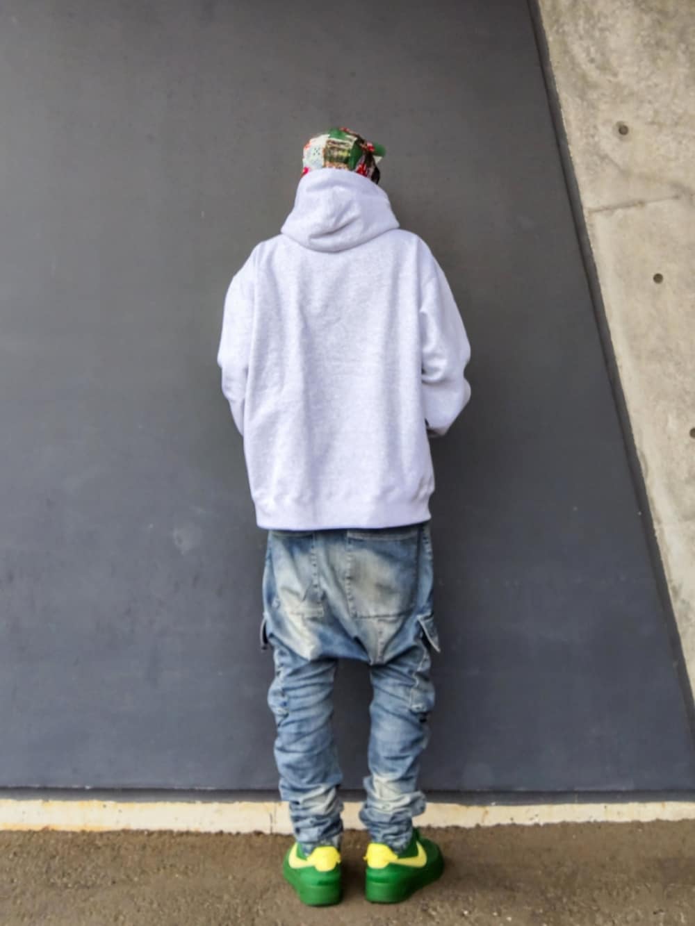 グレー系のパーカー、ブルー系のデニムパンツ、グリーン系のスニーカーを着用したメンズの冬コーディネートの3枚目の写真