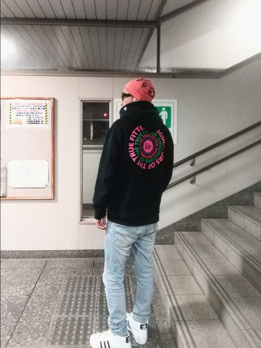 ブラック系のパーカー、ブルー系のデニムパンツ、ホワイト系のスニーカーを着用したメンズの春コーディネートの2枚目の写真