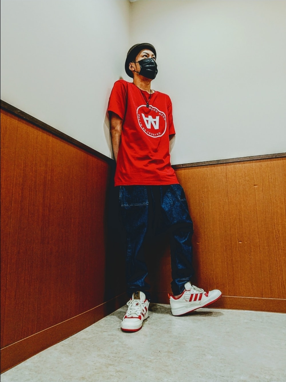 レッド系のTシャツ/カットソー、ブルー系のデニムパンツ、ホワイト系のスニーカーを着用したメンズの秋コーディネートの2枚目の写真