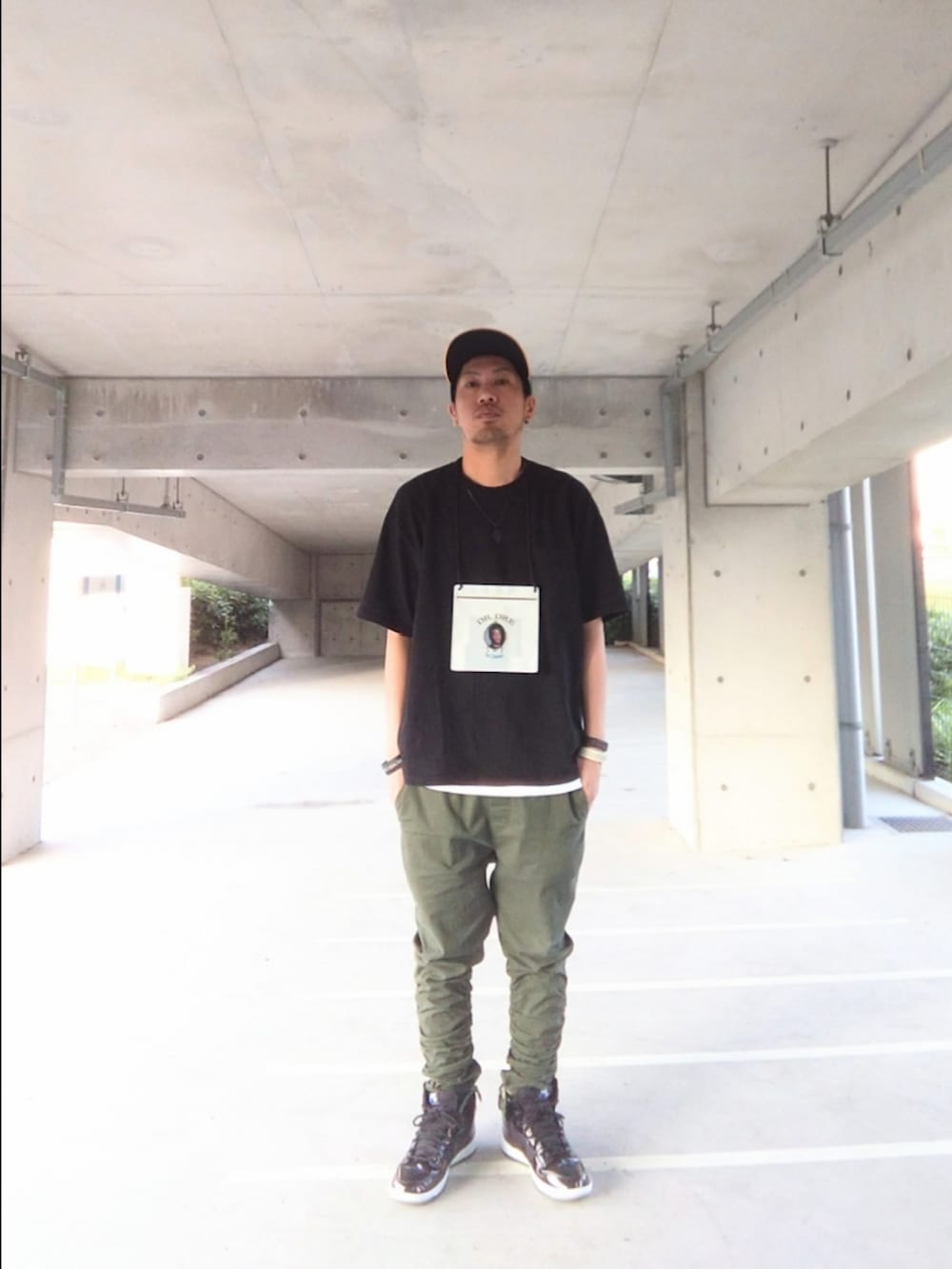 ブラック系のTシャツ/カットソー、グリーン系のパンツ、ブラック系のスニーカーを着用したメンズの夏コーディネートの2枚目の写真