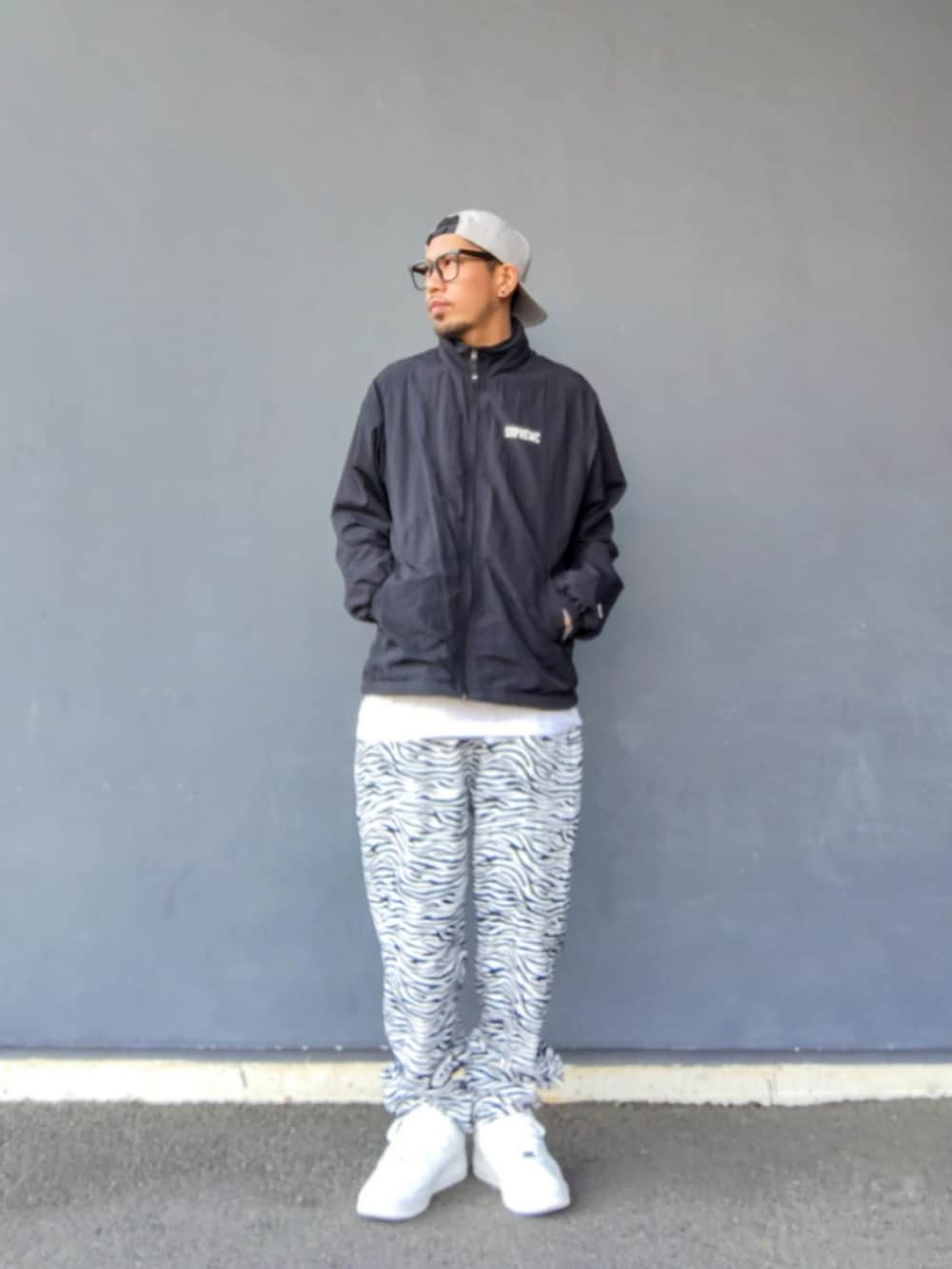 ブラック系のその他アウター、ホワイト系のその他パンツ、ホワイト系のスニーカーを着用したメンズの春コーディネートの2枚目の写真