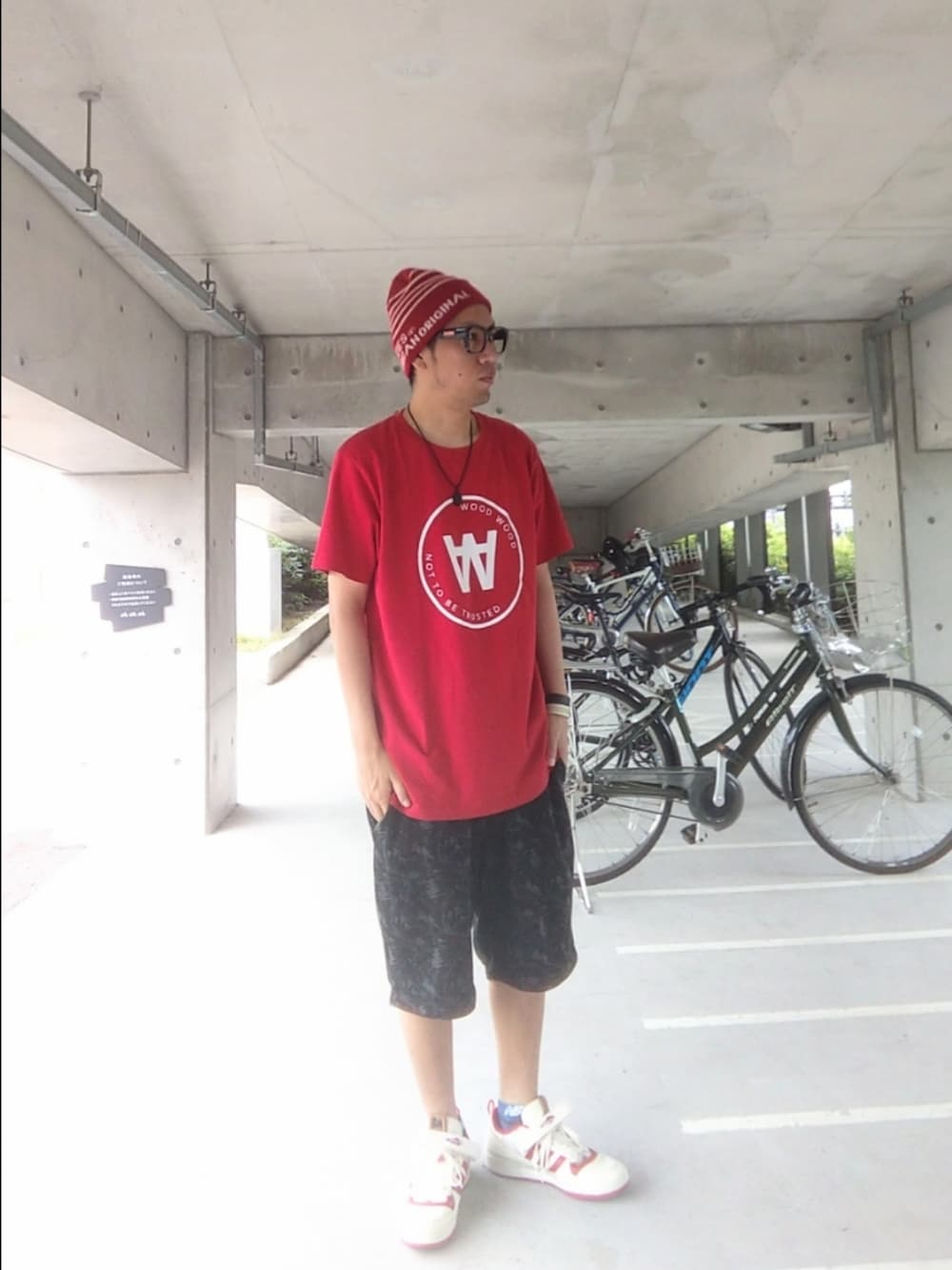 レッド系のTシャツ/カットソー、ブラック系のパンツ、ホワイト系のスニーカーを着用したメンズの夏コーディネートの2枚目の写真