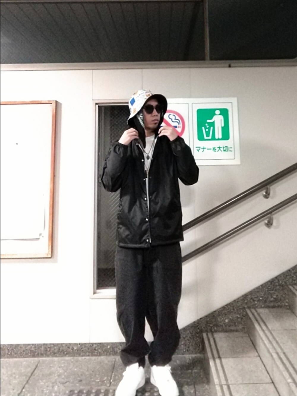 ホワイト系のスニーカー、ブルー系のナイロンジャケット、ブラック系のデニムパンツを着用したメンズの春コーディネートの2枚目の写真