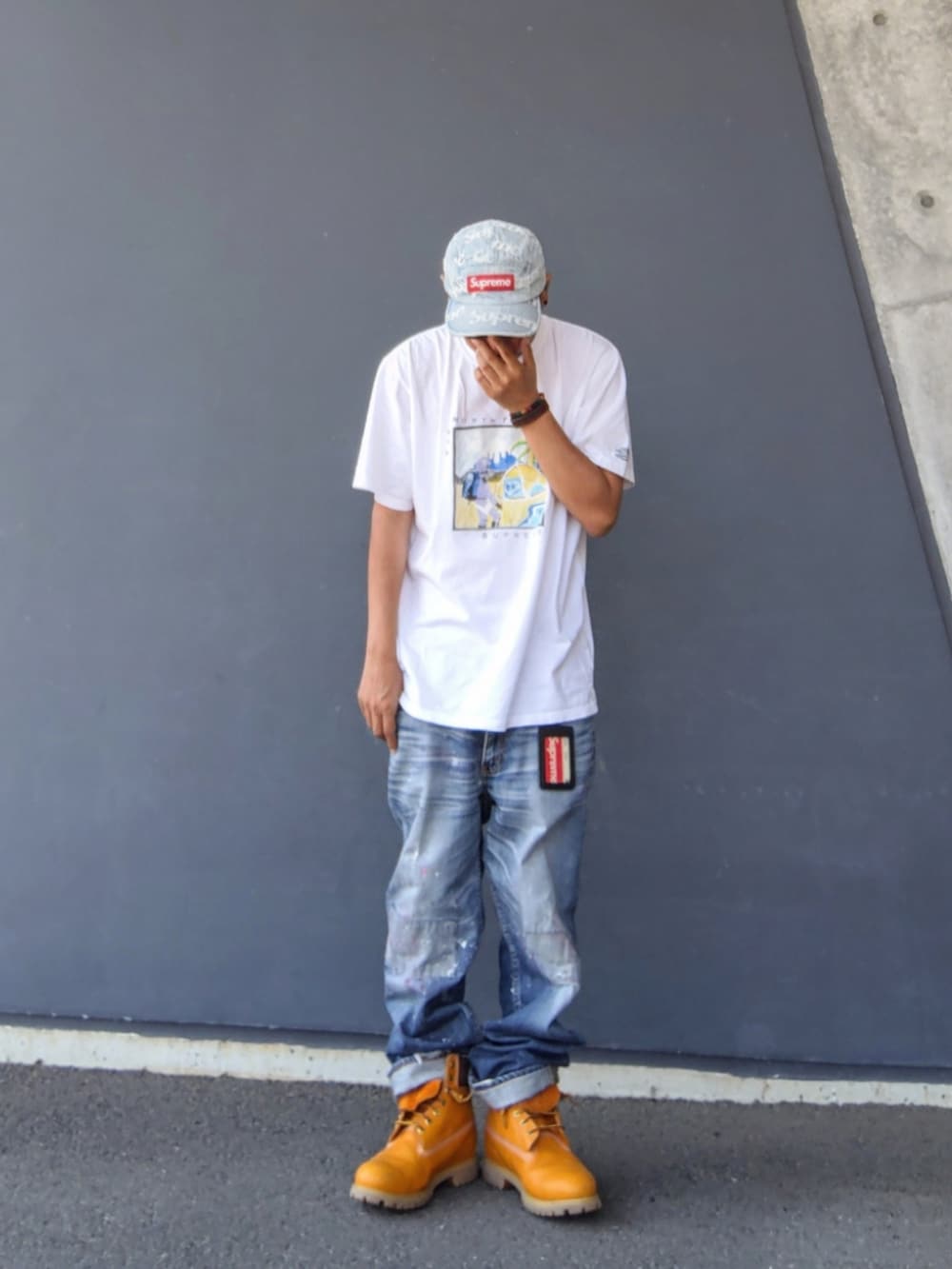 ホワイト系のTシャツ/カットソー、ブルー系のデニムパンツ、イエロー系のブーツを着用したメンズの夏コーディネートの2枚目の写真