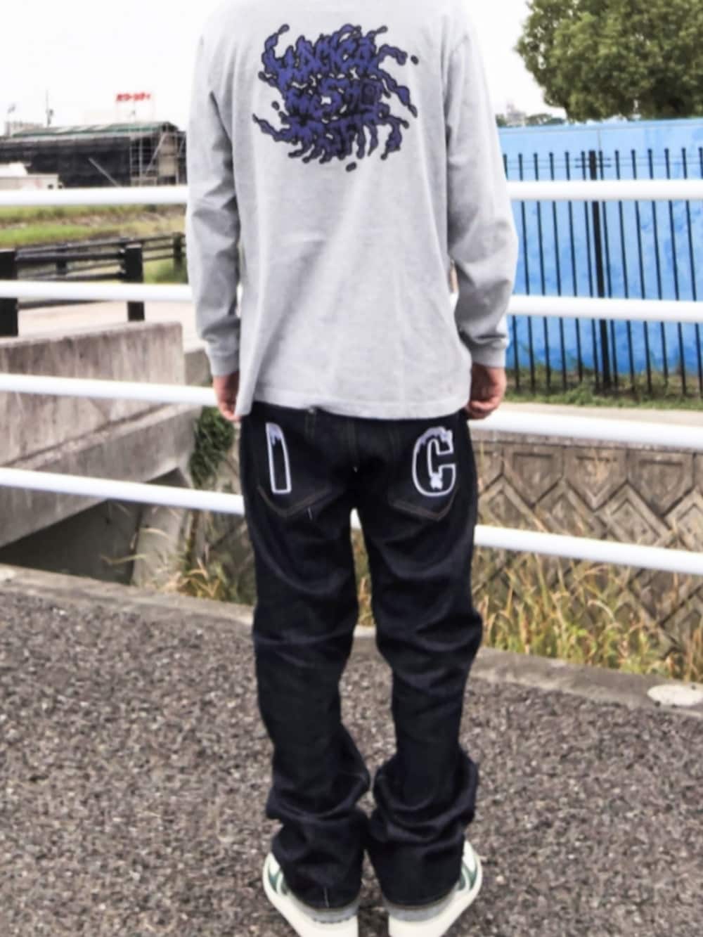 グレー系のTシャツ/カットソー、ブルー系のデニムパンツ、ホワイト系のスニーカーを着用したメンズの秋コーディネートの3枚目の写真