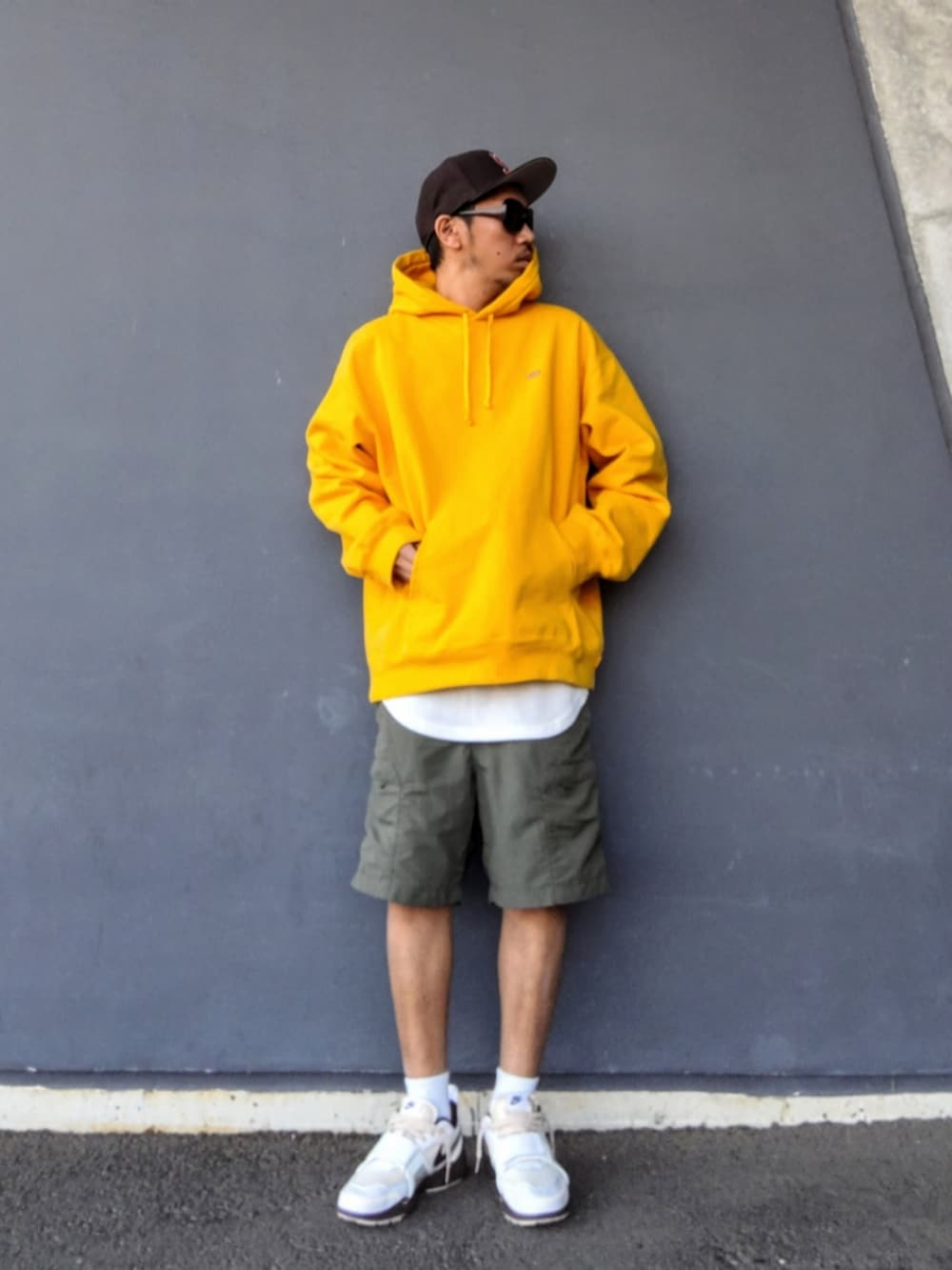 イエロー系のパーカー、ホワイト系のタンクトップ、グリーン系のその他パンツを着用したメンズの春コーディネートの2枚目の写真