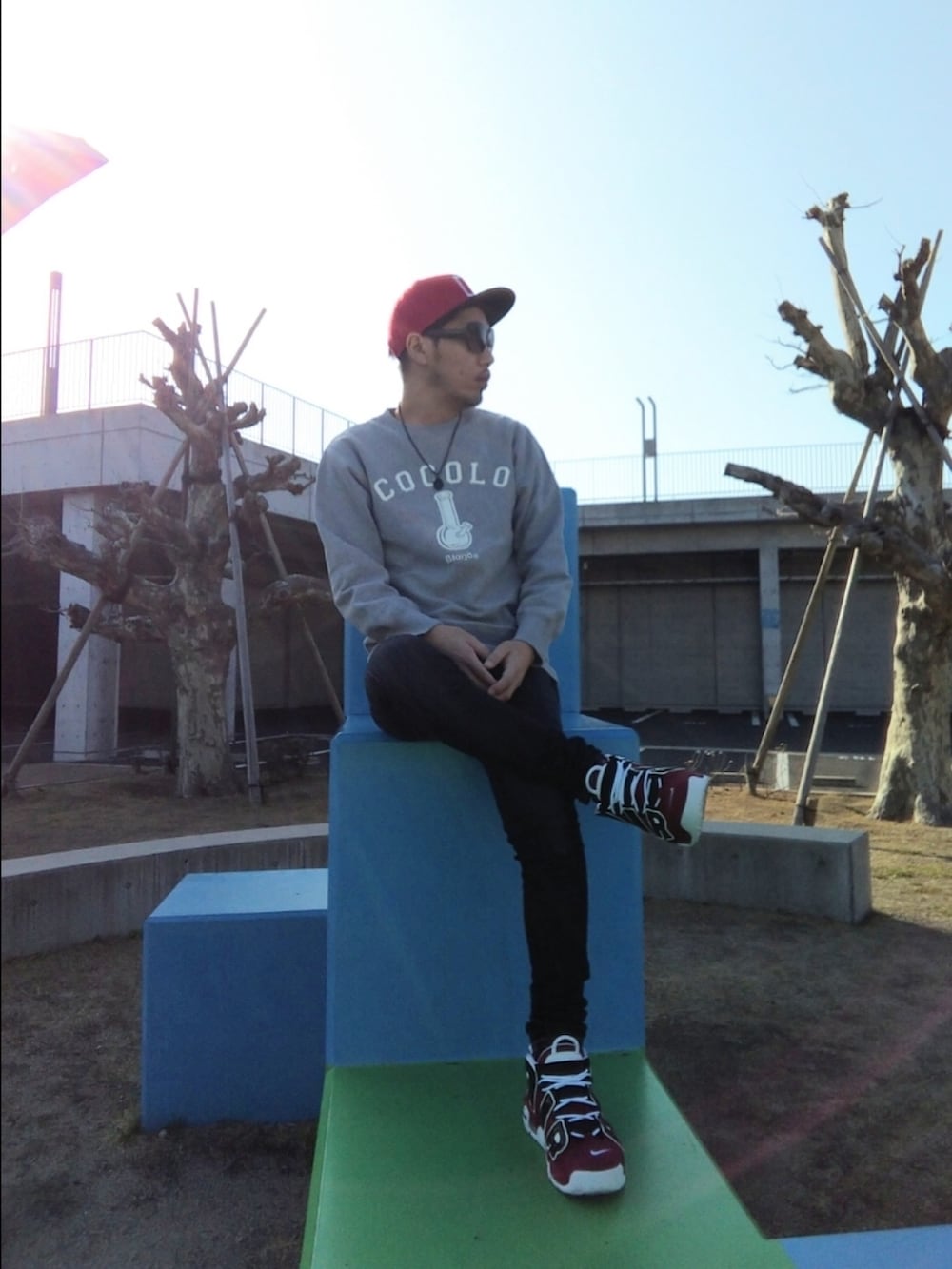 グレー系のスウェット、ブルー系のデニムパンツ、レッド系のスニーカーを着用したメンズの春コーディネートの3枚目の写真