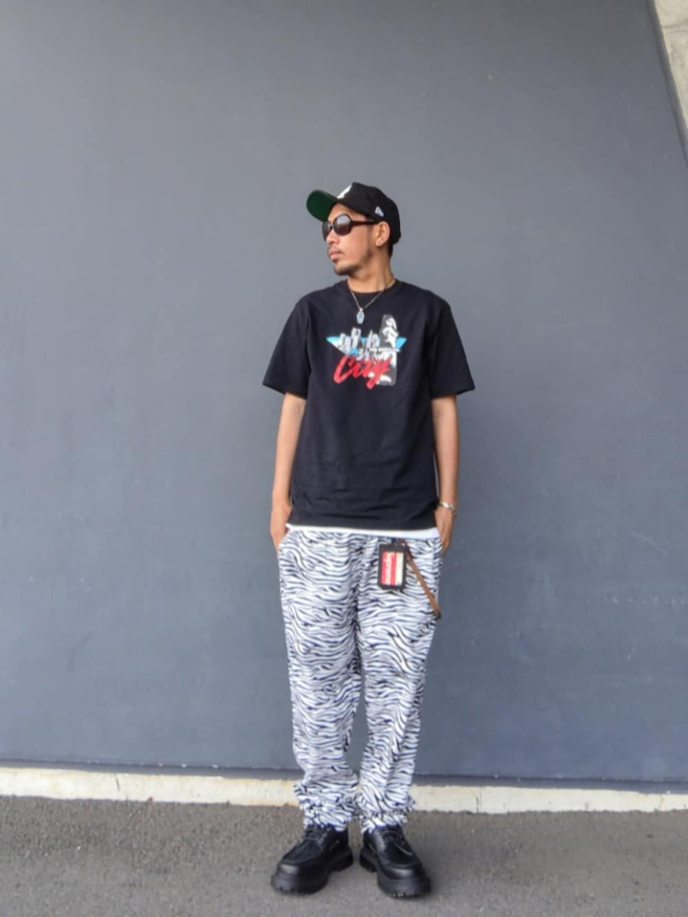 ブラック系のTシャツ/カットソー、ホワイト系のその他パンツ、ブラック系のモカシン/デッキシューズを着用したメンズの夏コーディネートの2枚目の写真