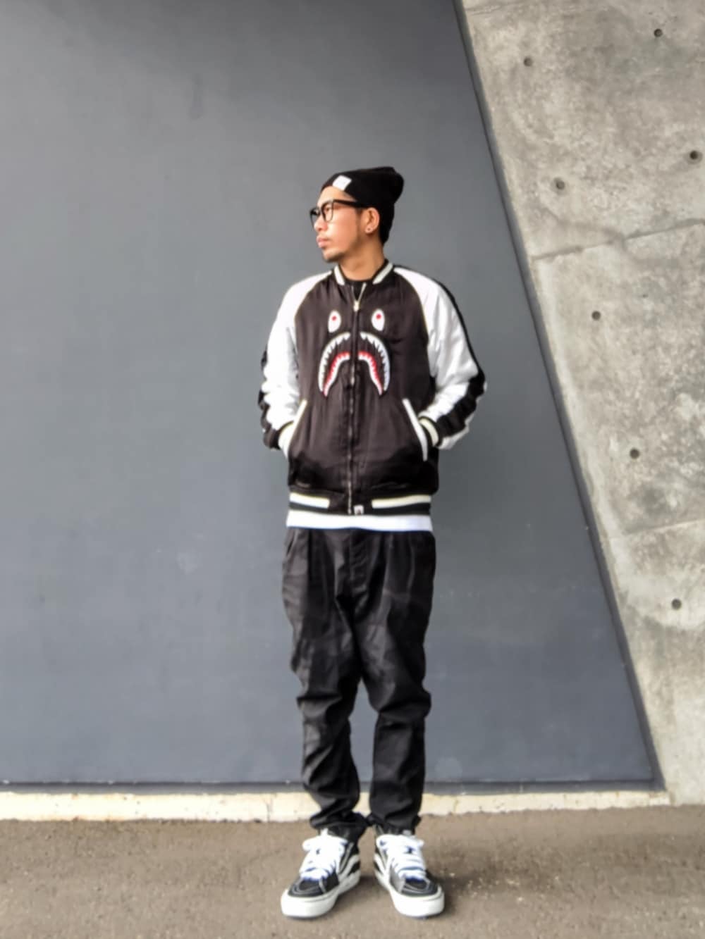 ブラック系のスカジャン、ブラック系のパンツ、ブラック系のスニーカーを着用したメンズの春コーディネートの2枚目の写真