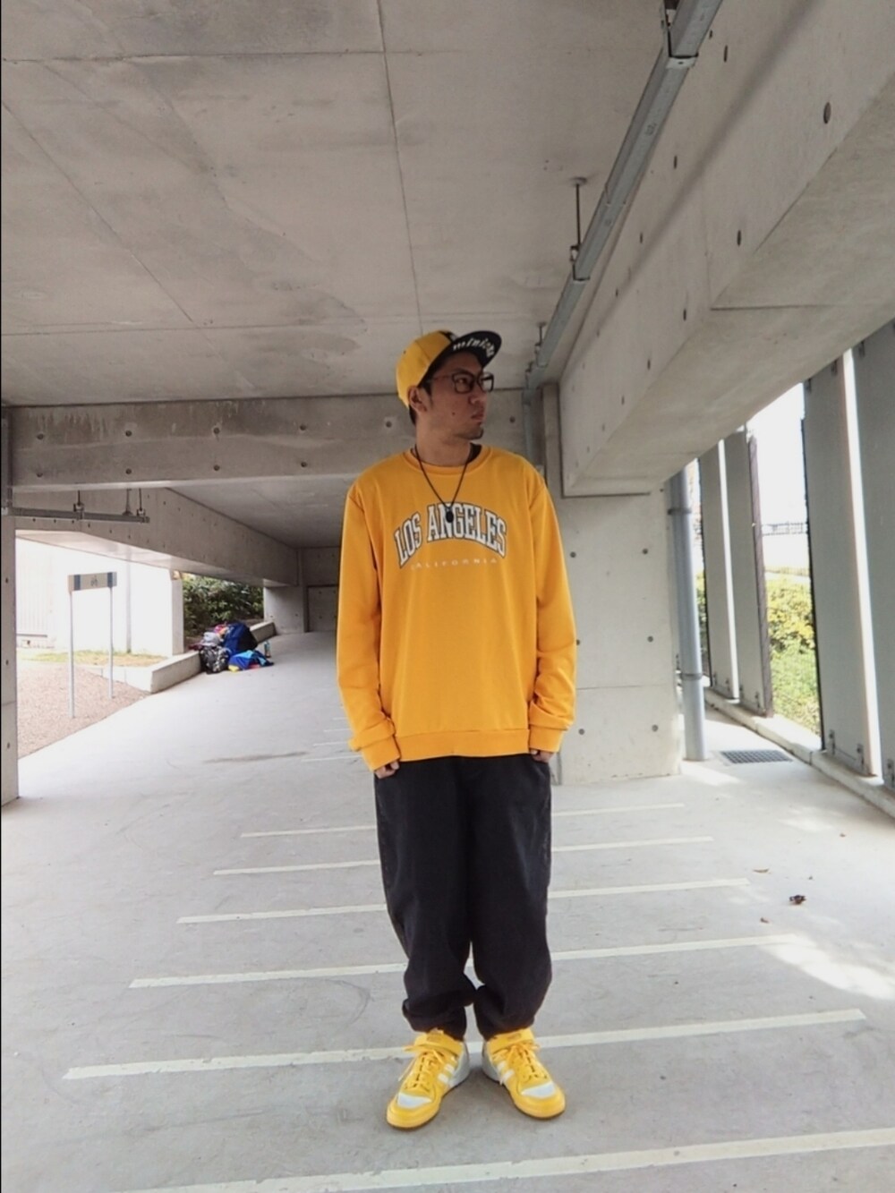 イエロー系のスウェット、ブラック系のデニムパンツ、イエロー系のスニーカーを着用したメンズの春コーディネートの2枚目の写真