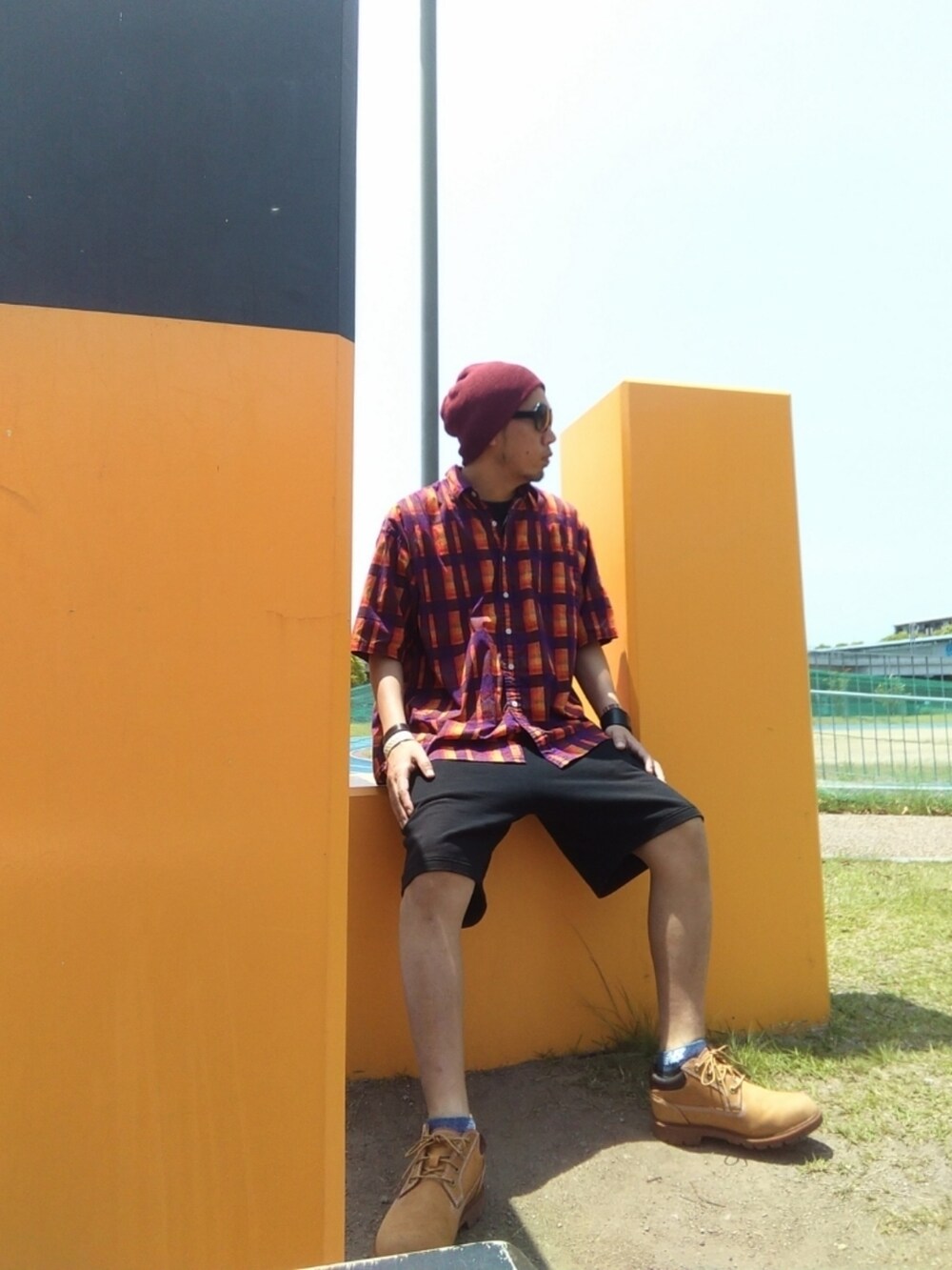 イエロー系のブーツ、ブラック系のその他パンツ、オレンジ系のシャツ/ブラウスを着用したメンズの夏コーディネートの2枚目の写真