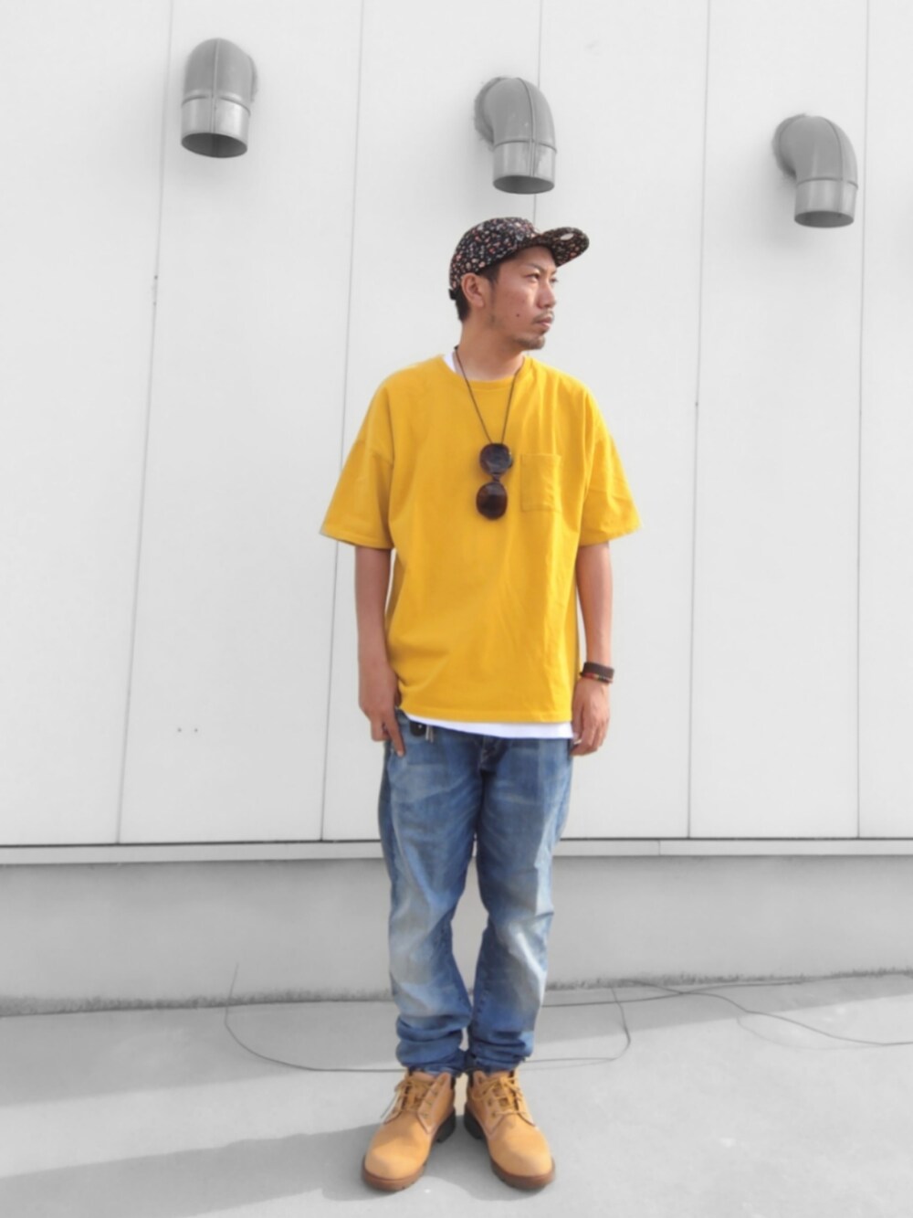 イエロー系のTシャツ/カットソー、ブルー系のデニムパンツ、イエロー系のブーツを着用したメンズの秋コーディネートの2枚目の写真