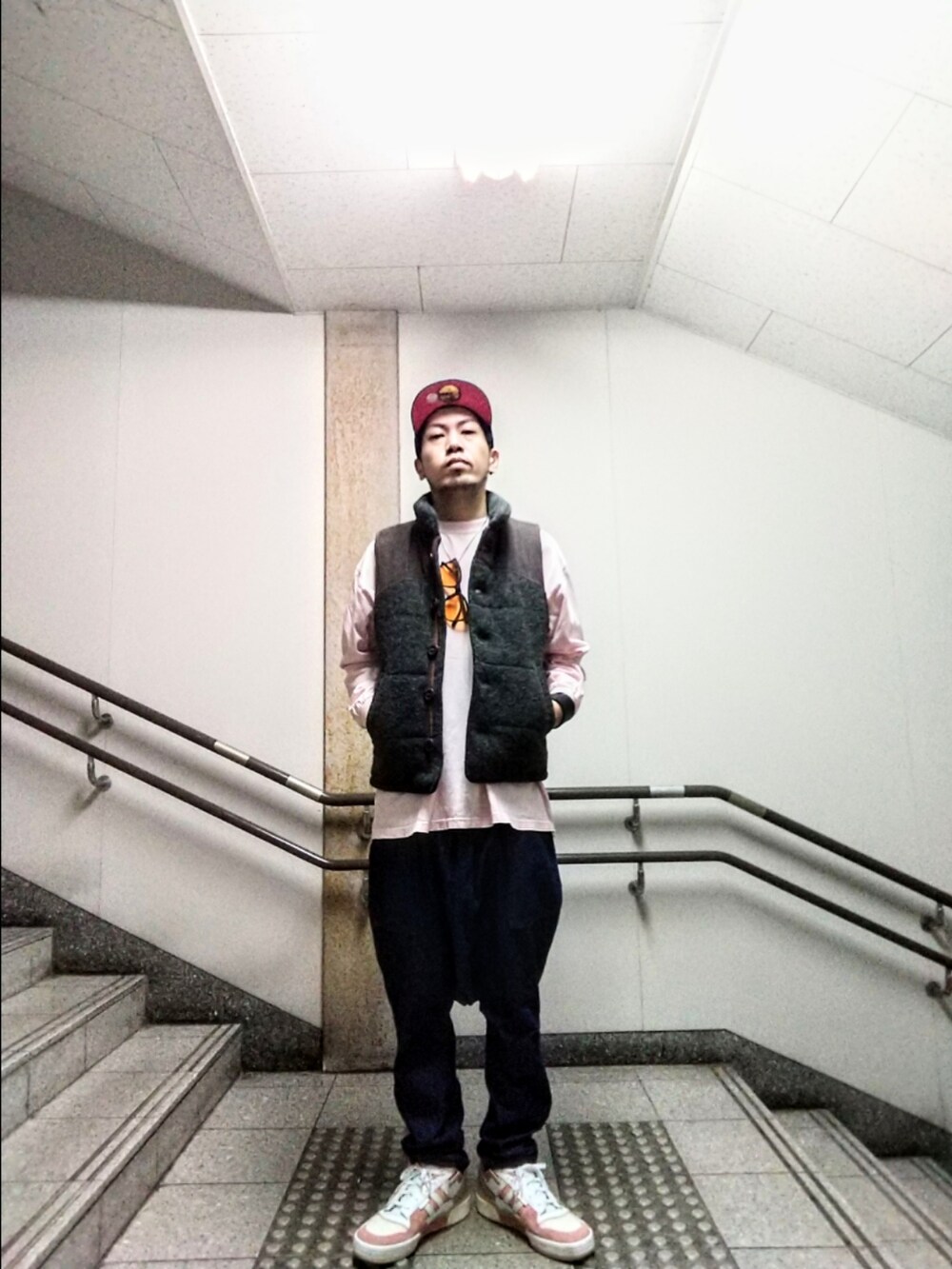 グレー系のベスト、ピンク系のTシャツ/カットソー、ブルー系のデニムパンツを着用したメンズの秋コーディネートの2枚目の写真