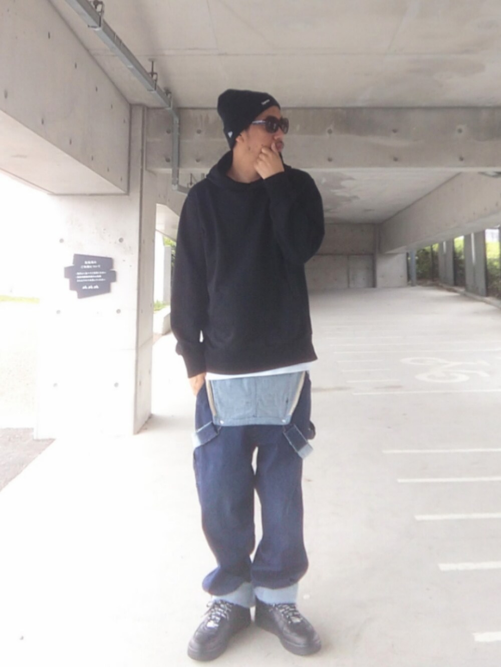 ブラック系のパーカー、ブルー系のサロペット/オーバーオール、ブラック系のスニーカーを着用したメンズの春コーディネートの2枚目の写真