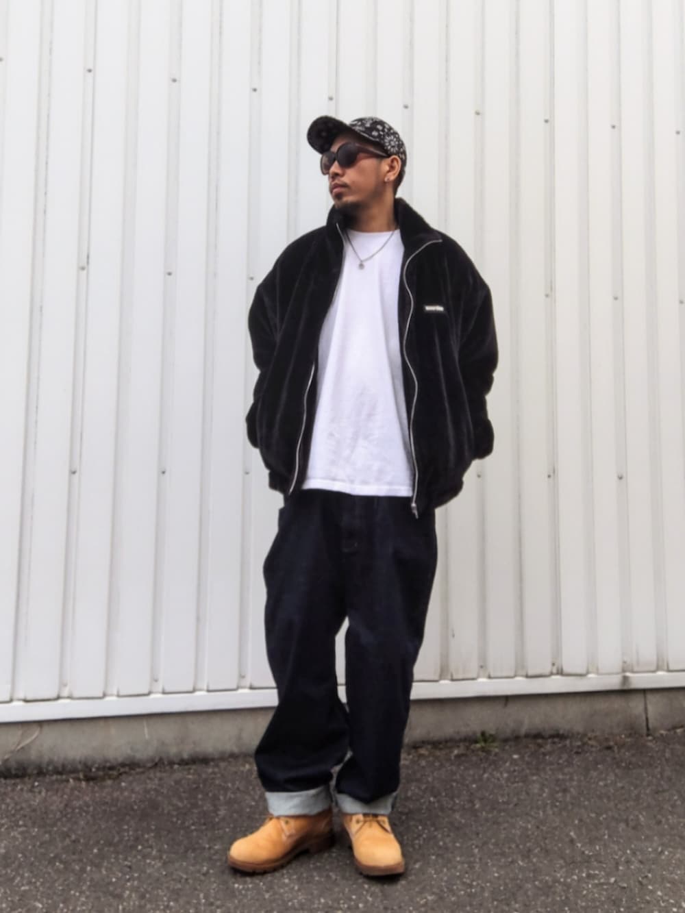 ブラック系のブルゾン、ホワイト系のTシャツ/カットソー、ブルー系のデニムパンツを着用したメンズの冬コーディネートの2枚目の写真