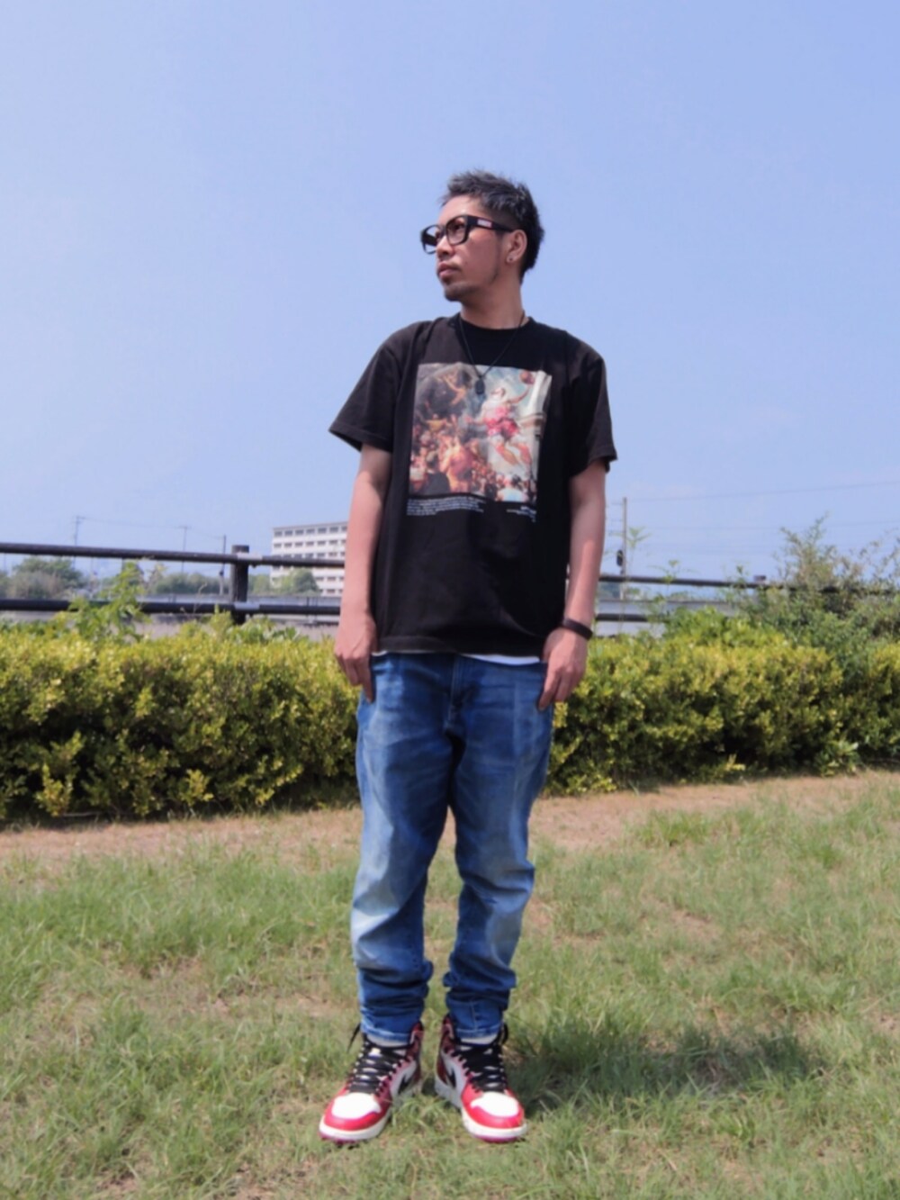 ブラック系のTシャツ/カットソー、ブルー系のデニムパンツ、レッド系のスニーカーを着用したメンズの夏コーディネートの3枚目の写真