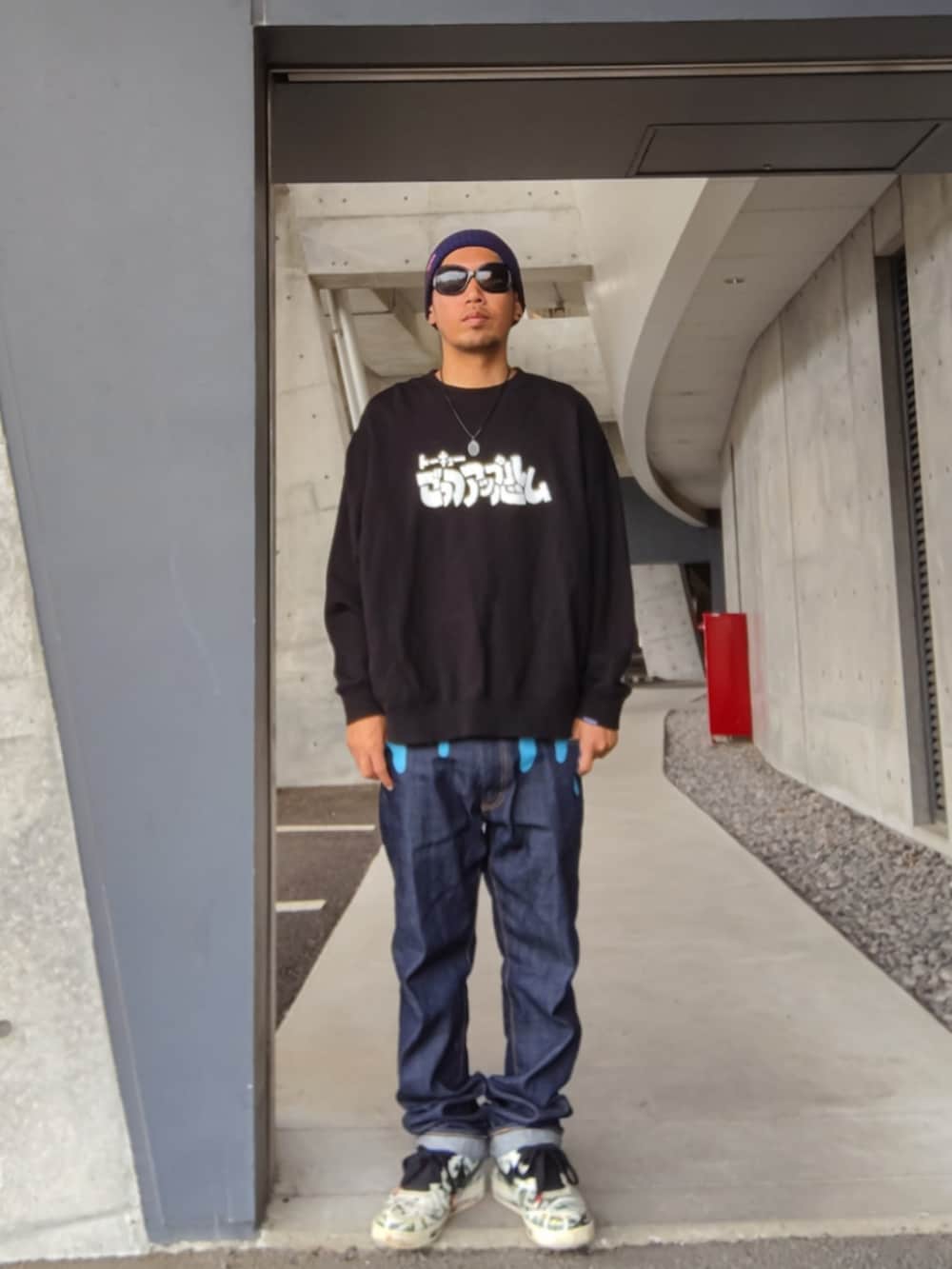 ブラック系のスウェット、ブルー系のデニムパンツ、ホワイト系のスニーカーを着用したメンズの秋コーディネートの3枚目の写真