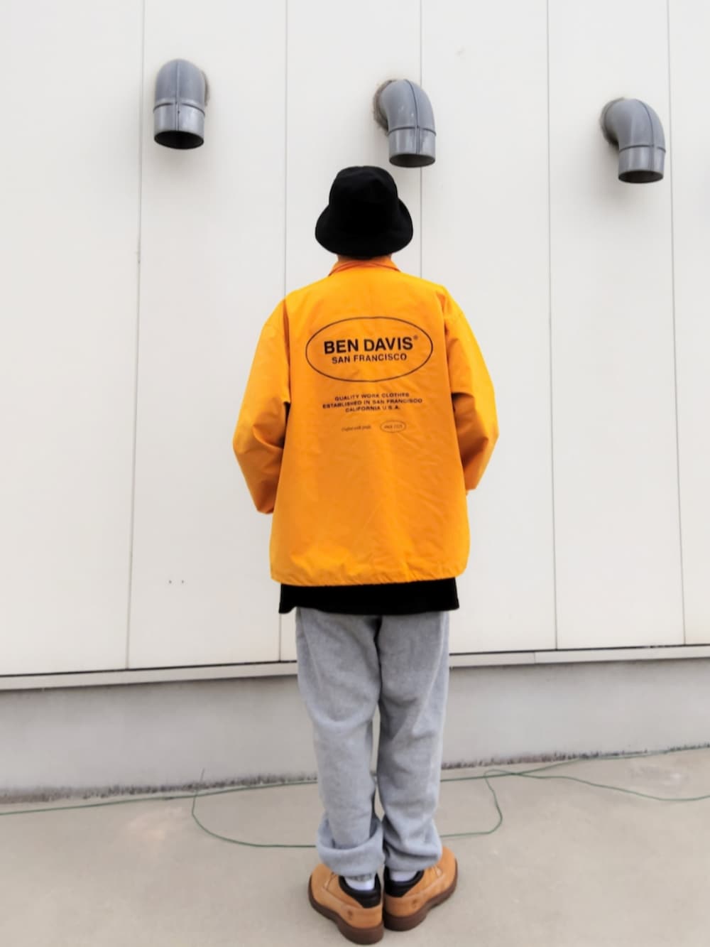 イエロー系のナイロンジャケット、ブラック系のTシャツ/カットソー、グレー系のスウェットパンツを着用したメンズの秋コーディネートの2枚目の写真